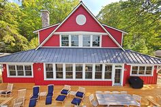 a red house with blue chairs on the deck