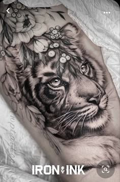 a black and white tiger with flowers on it's head is shown in this tattoo