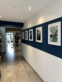 an empty hallway with pictures on the wall and tables in front of it, along with chairs