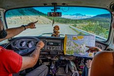 two people sitting in the passenger seat of a vehicle looking at a map and pointing to it