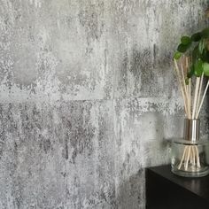 a vase filled with flowers on top of a table next to a wall covered in cement