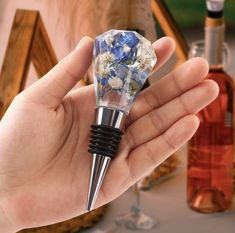 a person holding a wine bottle stopper with flowers on it