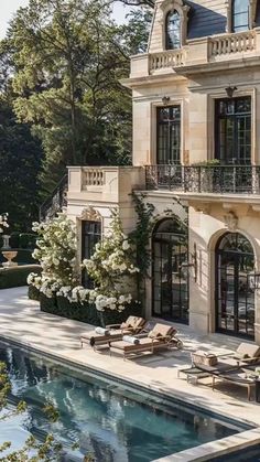 a large house with a pool in front of it and lots of windows on the side