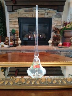 a glass vase sitting on top of a wooden table in front of a fire place