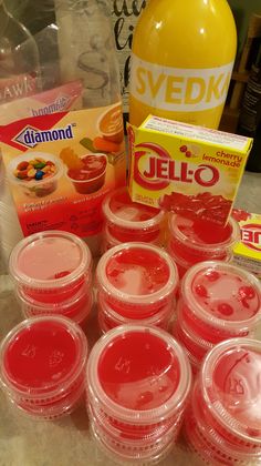 many jello cups are lined up on the counter next to a bottle of orange juice