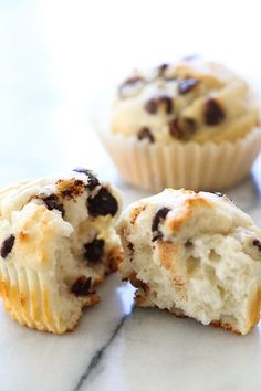 two chocolate chip muffins cut in half on a marble surface