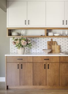 a kitchen with wooden cabinets and white tile backsplash, flowers on the counter