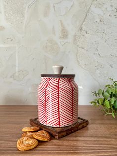 a red and white canister sitting on top of a wooden table next to some cookies