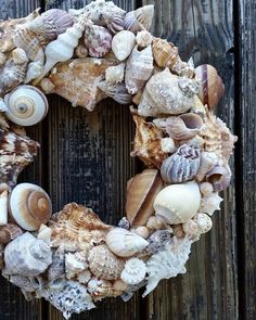 a wreath made out of seashells sitting on top of a wooden fence