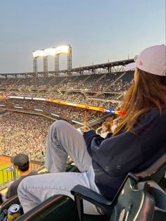 a woman sitting in a chair at a baseball game looking out into the stands and crowd