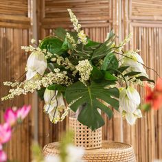 a vase filled with white flowers on top of a wooden table covered in wicker