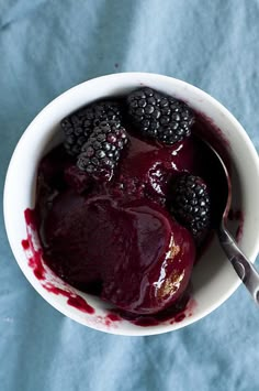 a bowl filled with berries and ice cream on top of a blue cloth covered table