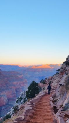 a person walking down a trail at the edge of a cliff