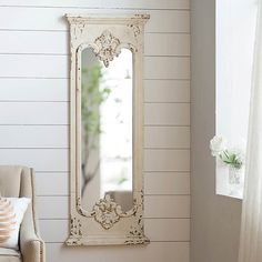 a white mirror sitting on top of a wall next to a chair in a room