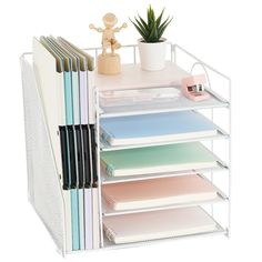 a white metal shelf with many files and folders on top of it next to a potted plant