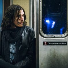 a man with long hair sitting on a train