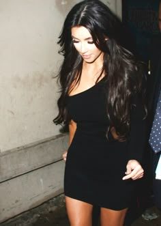 a woman in a short black dress walking down the street