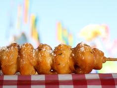 some food is sitting on a red and white checkered tablecloth with a carnival in the background