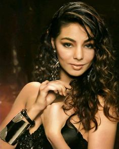 a beautiful young woman in a black dress posing for the camera with her hand on her shoulder