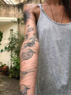 a woman's arm with tattoos on it in front of some plants and trees