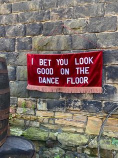 a sign that says i bet you look good on the dance floor hanging from a brick wall