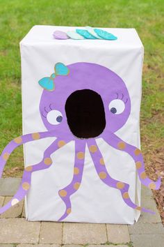 a cardboard box with an octopus painted on the front and side, sitting in grass