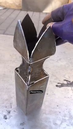 a metal object that is sitting on the ground in front of someone's hand