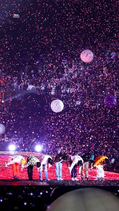 a group of people standing on top of a stage under confetti filled sky