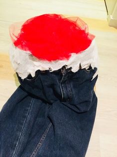 a red and white hat sitting on top of a pair of jeans