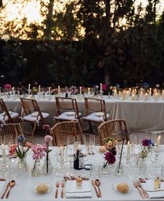 the tables are set for an event with candles and flower centerpieces on them