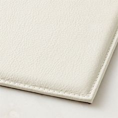 a white leather textured surface with stitching