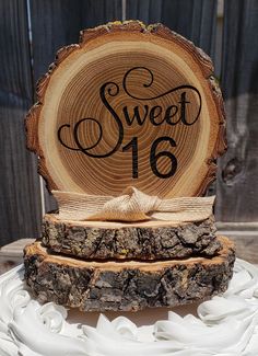 a wooden slice with the word sweet sixteen on it sitting on top of a cake