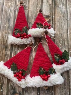 three crocheted christmas hats with holly berries and pine cones hanging from the top