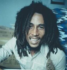 a man with dreadlocks sitting in front of a pile of dirt