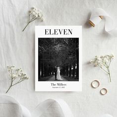 the cover of eleven magazine with white flowers and wedding rings on it next to ribbon