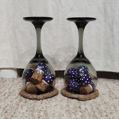 two vases with wine corks in them sitting on a carpeted floor next to a white wall