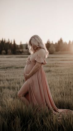 a pregnant woman is standing in a field