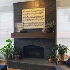 a living room with a brick fireplace and music sheet on the wall above it, surrounded by potted plants