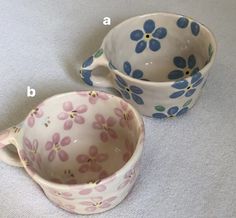 two bowls with flower designs on them sitting on a table next to the same bowl