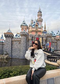 a woman sitting on a ledge in front of a castle