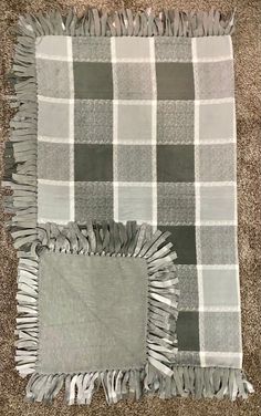 a gray and white checkered blanket with fringes on the floor next to it