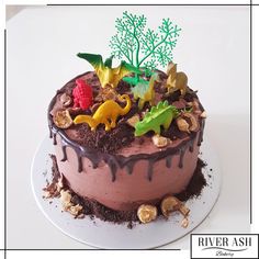 a cake with chocolate frosting and toy dinosaurs on top