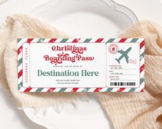 a christmas boarding pass sitting on top of a white plate next to a red and green striped napkin