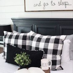 a bed with black and white plaid pillows on top of it next to an open book