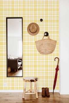 an umbrella, hat and boots are on the floor in front of a yellow plaid wall