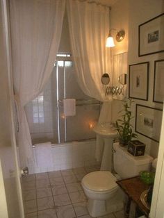 a bathroom with a toilet, sink and bathtub covered in white curtained drapes