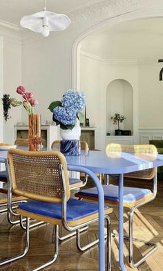 a dining room table with blue chairs and flowers