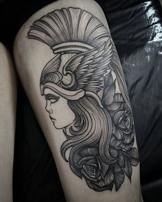 a woman's leg with a black and white tattoo design on her thigh, featuring a headdress