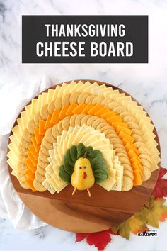 a thanksgiving cheese board on a wooden platter with crackers and a turkey figurine