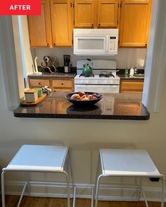 a kitchen with two stools and a bowl of fruit on the counter next to it